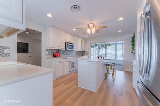 kitchen featuring white cabinets, decorative backsplash, a kitchen island, and appliances with stainless steel finishes