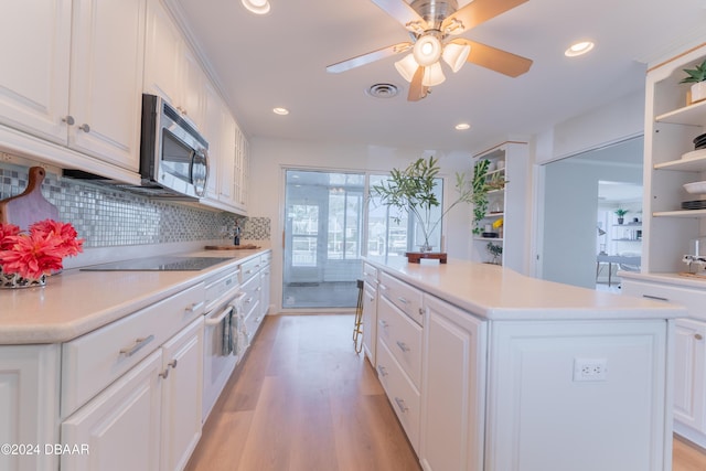 kitchen with a kitchen island, light hardwood / wood-style flooring, decorative backsplash, black electric stovetop, and white cabinets