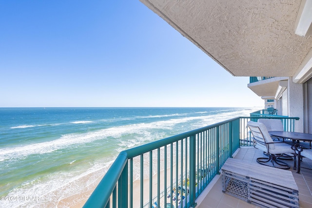 balcony featuring a view of the beach and a water view