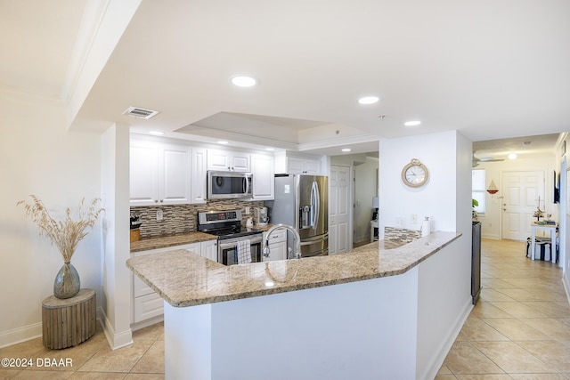 kitchen featuring kitchen peninsula, tasteful backsplash, stainless steel appliances, light tile patterned floors, and white cabinets