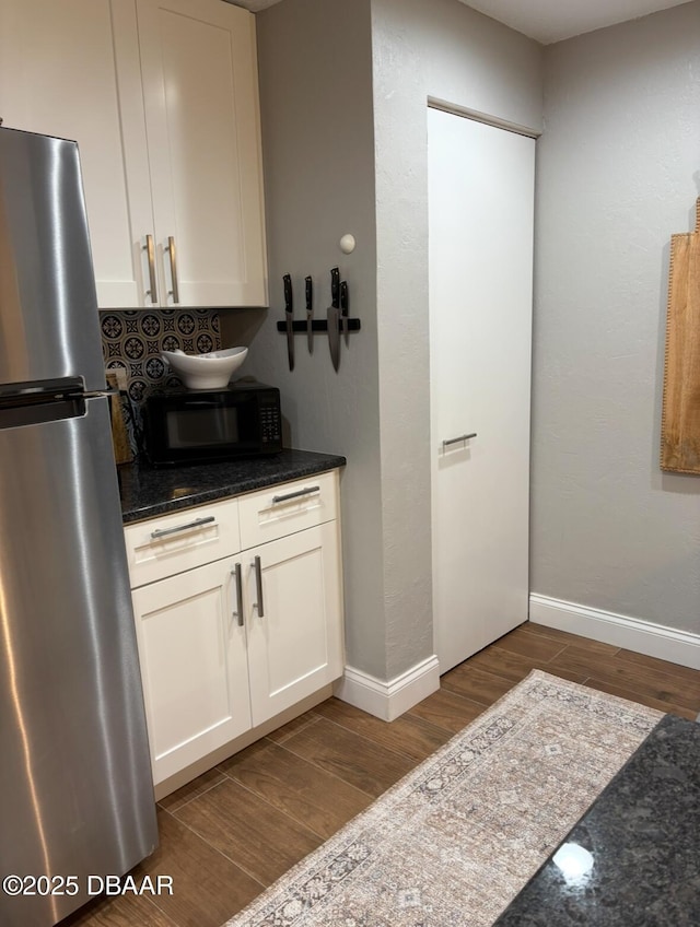 bar with stainless steel fridge, dark hardwood / wood-style floors, and dark stone counters