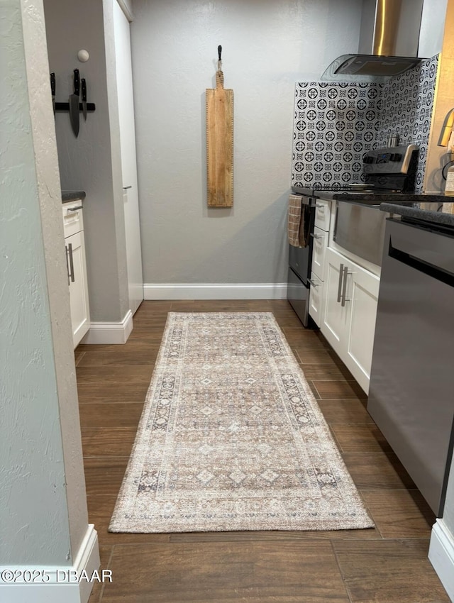 kitchen featuring dishwasher, dark hardwood / wood-style floors, white cabinets, decorative backsplash, and wall chimney exhaust hood