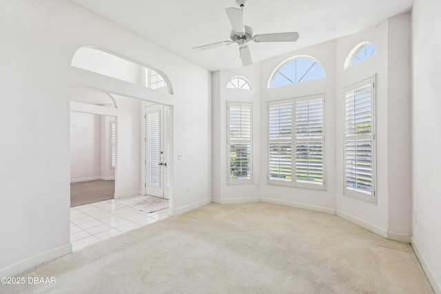tiled spare room featuring carpet flooring, a ceiling fan, and baseboards