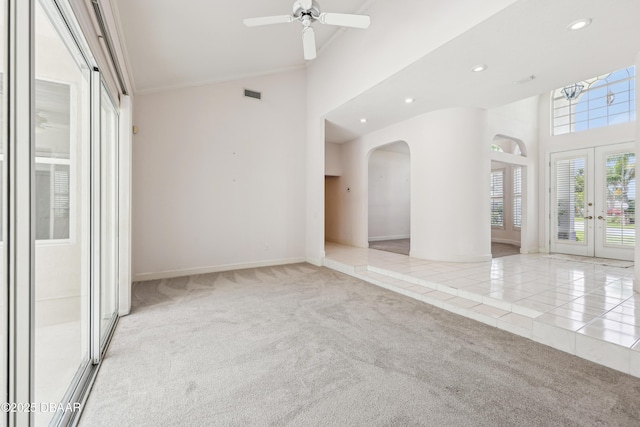 carpeted empty room with arched walkways, high vaulted ceiling, french doors, recessed lighting, and baseboards