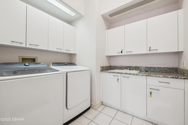 clothes washing area with cabinet space, a sink, light tile patterned floors, visible vents, and washer and clothes dryer