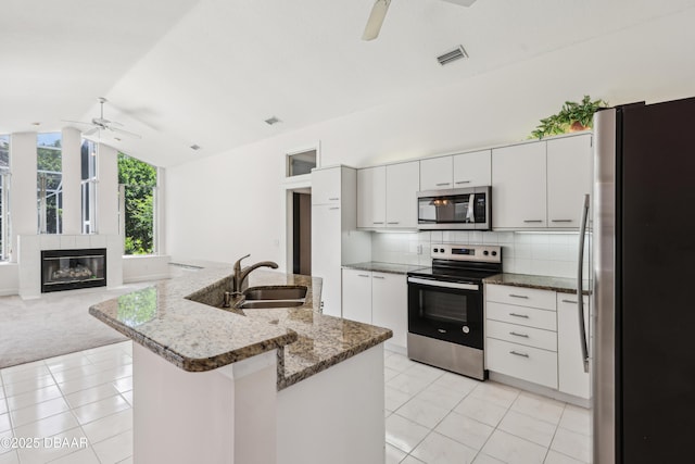 kitchen featuring visible vents, ceiling fan, a sink, vaulted ceiling, and stainless steel appliances