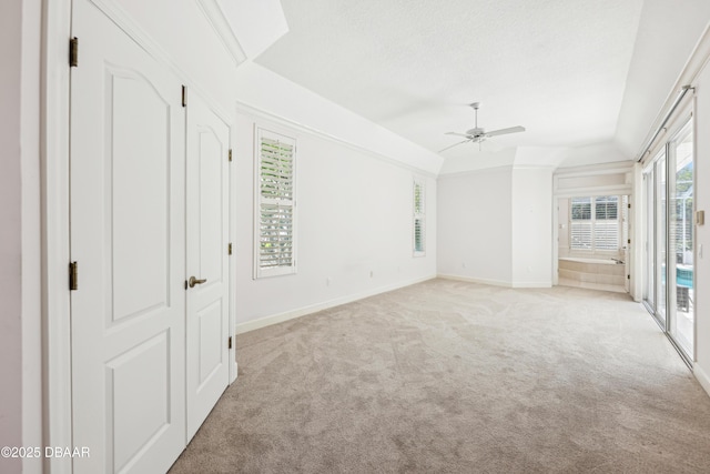 interior space with light colored carpet, access to exterior, a ceiling fan, baseboards, and lofted ceiling