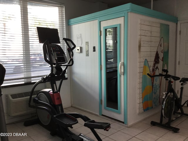 exercise area featuring light tile patterned flooring and a healthy amount of sunlight