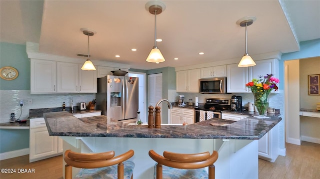 kitchen with pendant lighting, light hardwood / wood-style floors, white cabinets, and stainless steel appliances