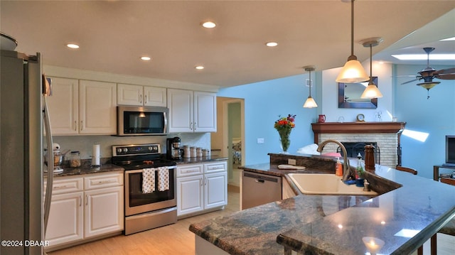 kitchen featuring white cabinetry, stainless steel appliances, an island with sink, pendant lighting, and light wood-type flooring