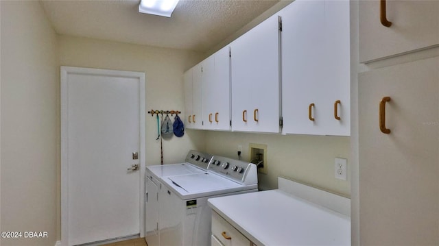 laundry area featuring washing machine and dryer, cabinets, and a textured ceiling