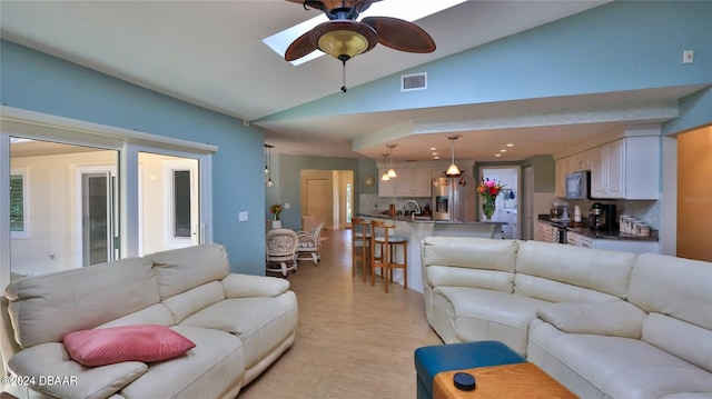 living room featuring ceiling fan, high vaulted ceiling, and a skylight