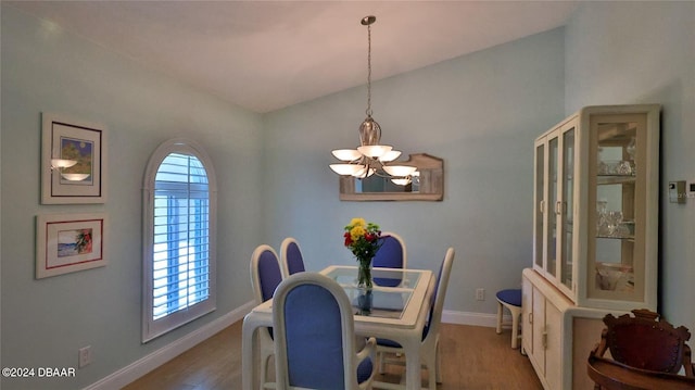 dining space featuring hardwood / wood-style flooring, plenty of natural light, lofted ceiling, and a notable chandelier