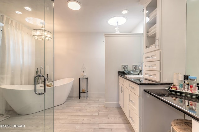 full bath with a freestanding tub, vanity, baseboards, and wood finished floors