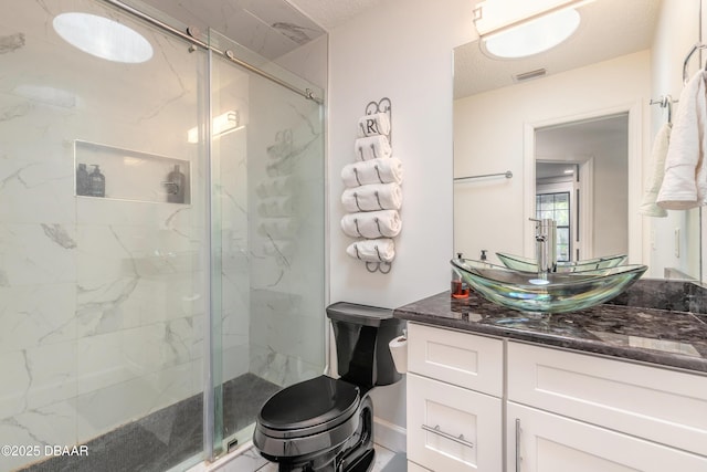 full bath featuring vanity, toilet, visible vents, and a marble finish shower