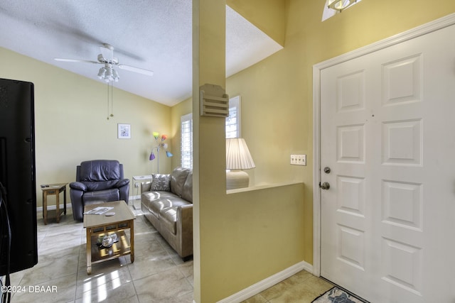 tiled foyer with ceiling fan, lofted ceiling, and a textured ceiling