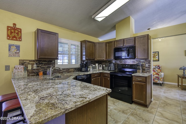 kitchen featuring kitchen peninsula, tasteful backsplash, dark brown cabinets, sink, and black appliances