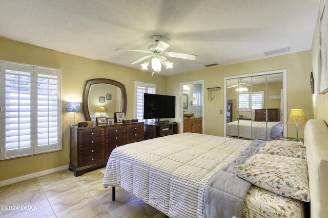 tiled bedroom with a textured ceiling, a closet, multiple windows, and ceiling fan