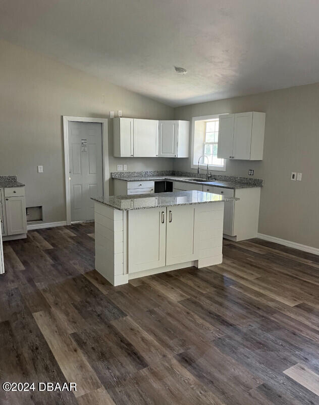 kitchen featuring sink, white cabinetry, lofted ceiling, and a kitchen island