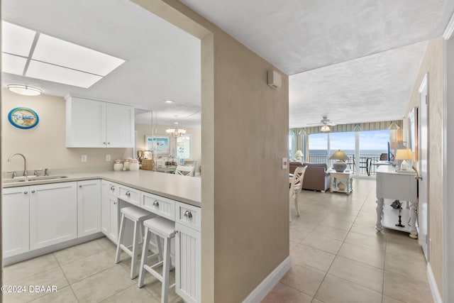 kitchen with white cabinetry, sink, and light tile patterned flooring