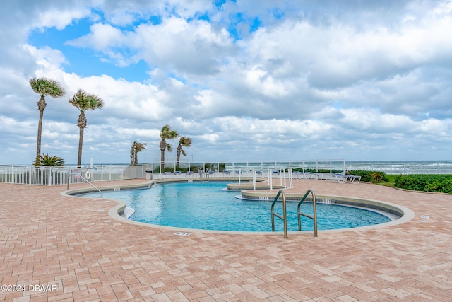 view of swimming pool featuring a water view and a patio area