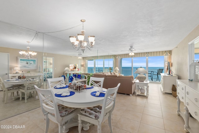 tiled dining room featuring ceiling fan with notable chandelier and a water view