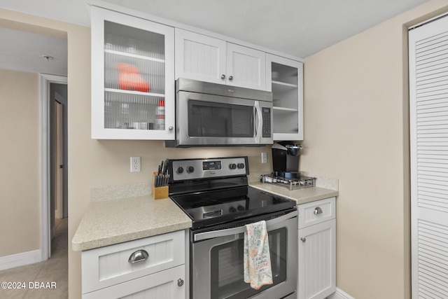 kitchen with white cabinetry, appliances with stainless steel finishes, and light tile patterned flooring