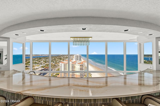 interior space featuring a water view, a beach view, and a notable chandelier