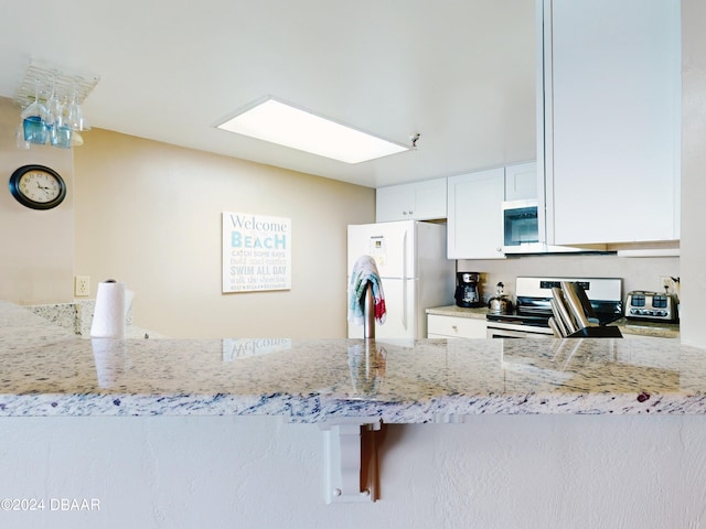 kitchen with light stone counters, white fridge, range with electric stovetop, white cabinetry, and kitchen peninsula