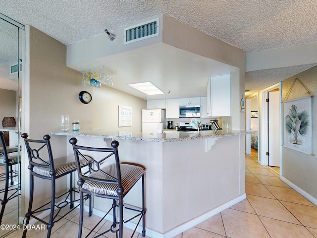 kitchen with kitchen peninsula, white cabinets, a breakfast bar, and appliances with stainless steel finishes