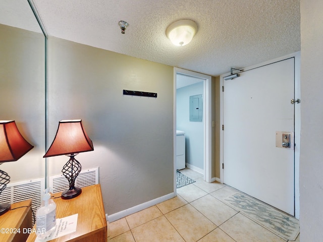 hall featuring electric panel, a textured ceiling, and light tile patterned floors