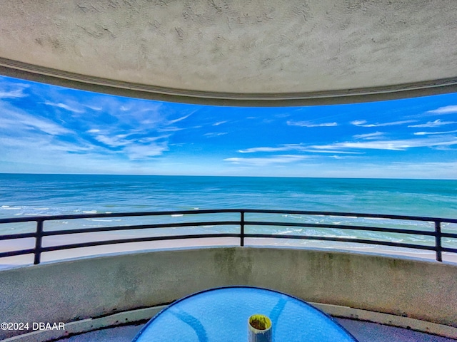 balcony featuring a view of the beach and a water view