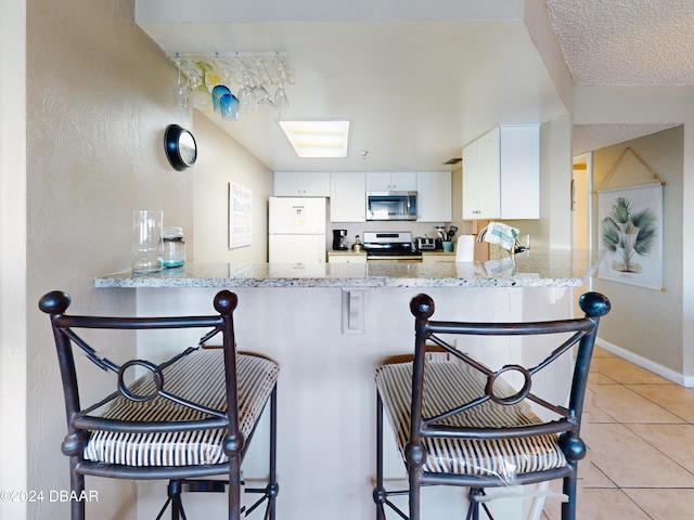 kitchen featuring stainless steel appliances, a kitchen breakfast bar, white cabinets, and kitchen peninsula