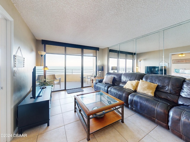 living room featuring a textured ceiling, light tile patterned floors, and floor to ceiling windows