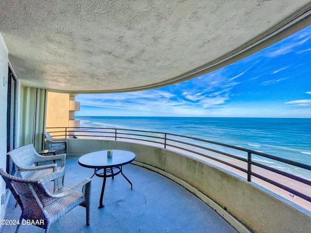 balcony featuring a beach view and a water view