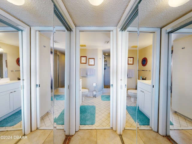 bathroom with tile patterned flooring, vanity, a textured ceiling, and toilet