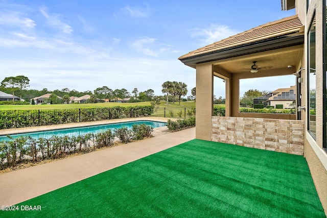 view of swimming pool with a patio area, a lawn, and ceiling fan