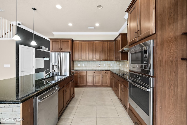 kitchen featuring sink, appliances with stainless steel finishes, tasteful backsplash, dark stone counters, and pendant lighting