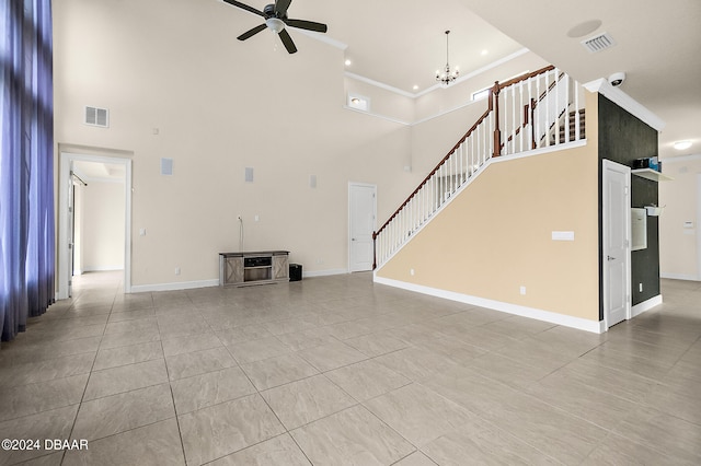 unfurnished living room with a high ceiling, ceiling fan with notable chandelier, and crown molding