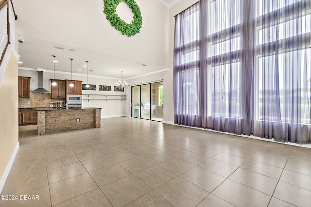 unfurnished living room with ornamental molding, an inviting chandelier, light tile patterned flooring, and plenty of natural light