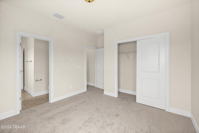 unfurnished bedroom featuring light colored carpet and a closet