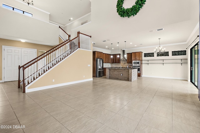 unfurnished living room with a notable chandelier, light tile patterned floors, and crown molding