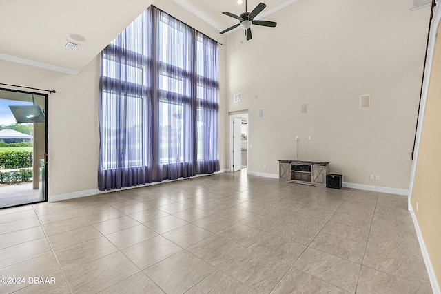 unfurnished living room featuring a high ceiling, ornamental molding, light tile patterned floors, and ceiling fan