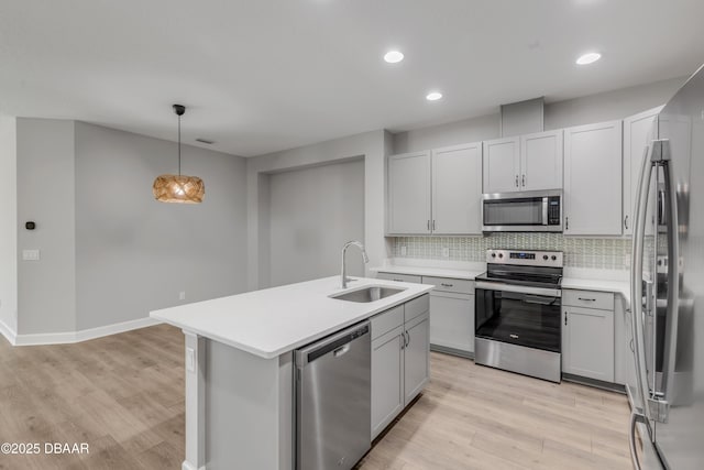 kitchen with decorative backsplash, sink, pendant lighting, stainless steel appliances, and a center island with sink