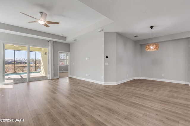 unfurnished room featuring light hardwood / wood-style floors, ceiling fan, and a raised ceiling