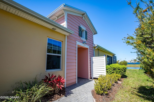 entrance to property featuring a water view, stucco siding, and a yard