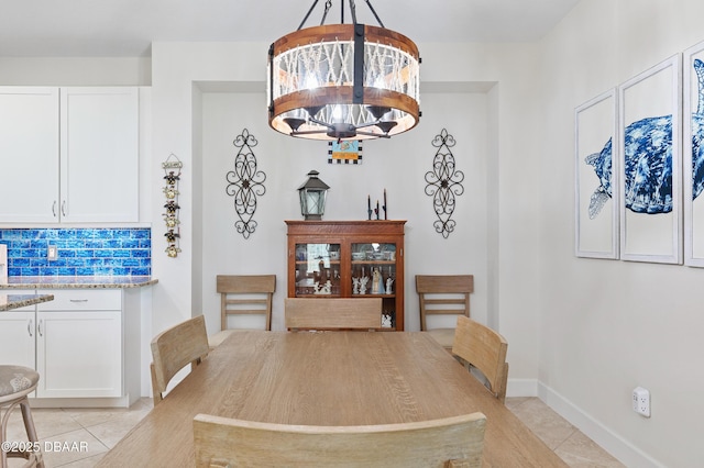 dining space featuring light tile patterned floors, baseboards, and a notable chandelier