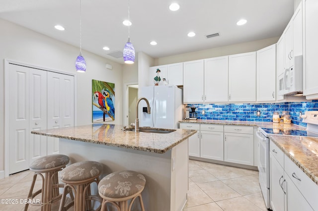 kitchen with white appliances, visible vents, light stone countertops, white cabinetry, and a sink