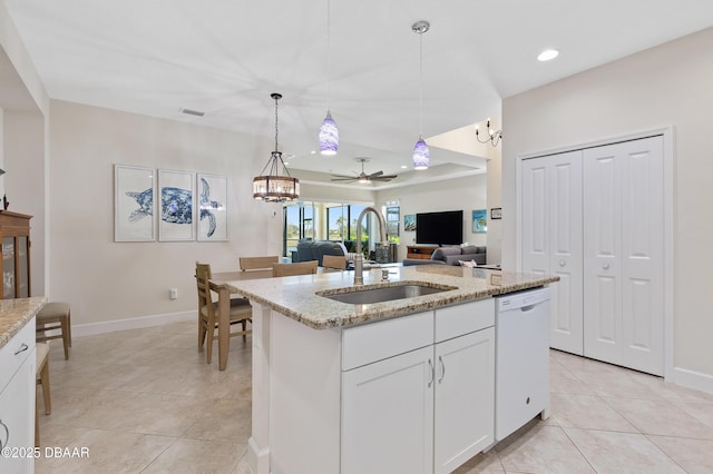 kitchen with light stone counters, pendant lighting, light tile patterned flooring, white dishwasher, and a sink