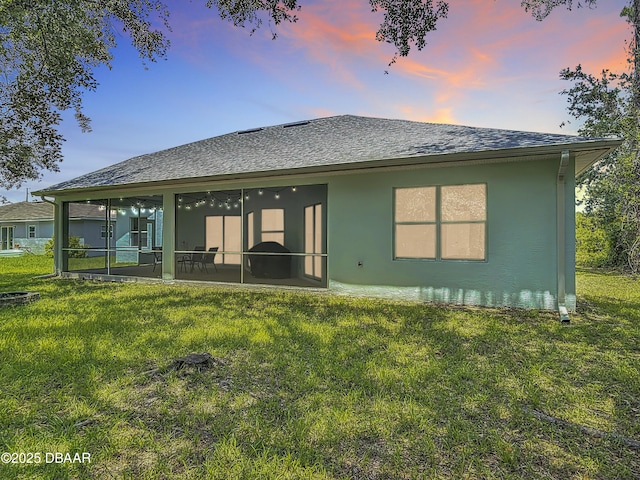 12 Kathleen Trl, Palm Coast, FL 32164 - back of property featuring stucco siding, a lawn, a shingled roof, and a sunroom